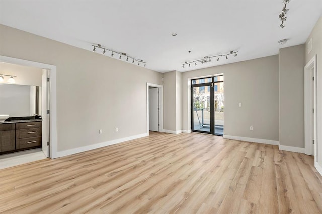 unfurnished bedroom featuring access to exterior, ensuite bathroom, baseboards, and light wood finished floors