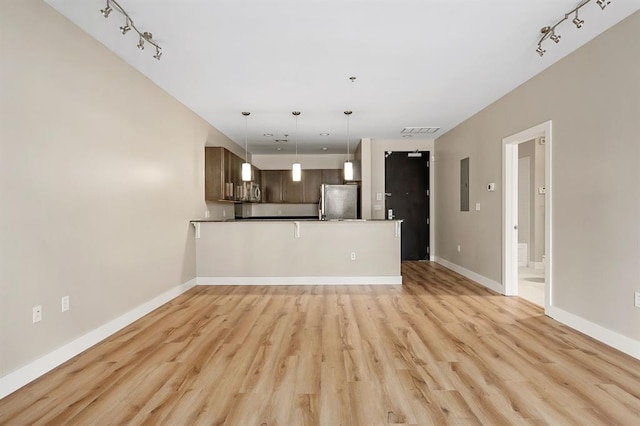 unfurnished living room featuring visible vents, baseboards, rail lighting, and light wood finished floors
