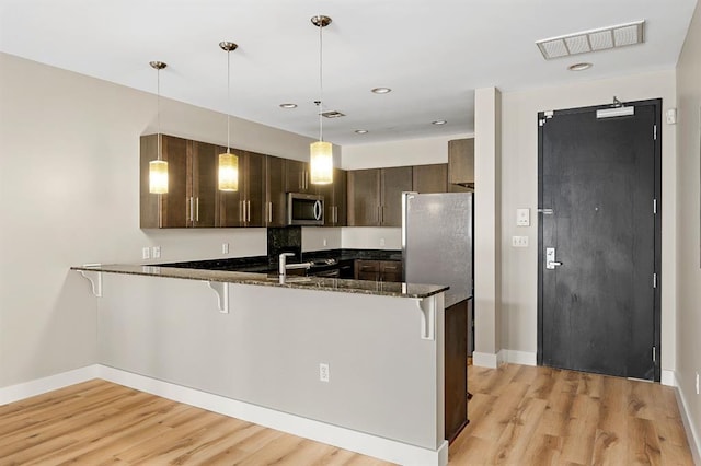kitchen with visible vents, appliances with stainless steel finishes, a breakfast bar, and a peninsula