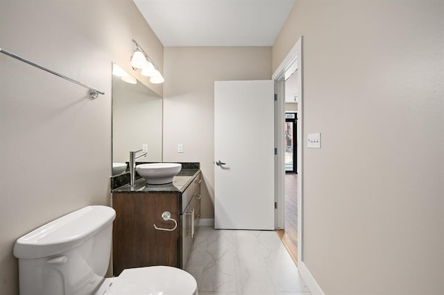 half bath featuring marble finish floor, toilet, vanity, and baseboards