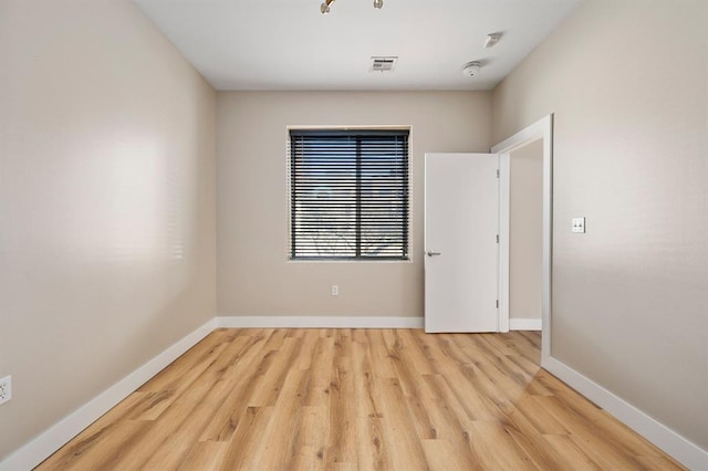 spare room featuring visible vents, baseboards, and wood finished floors