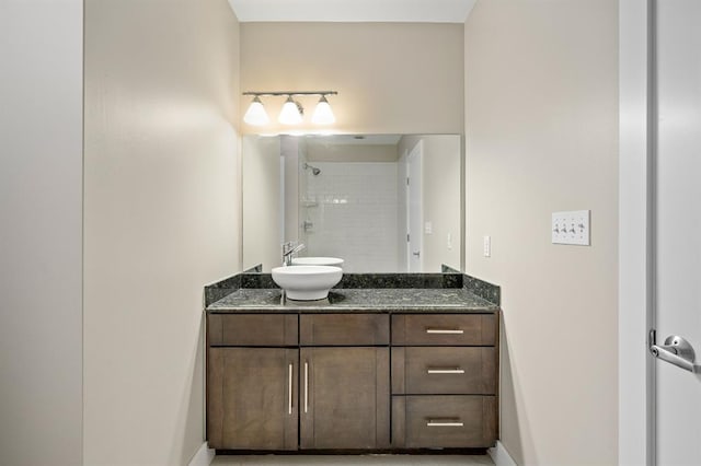 full bath featuring baseboards, tiled shower, and vanity