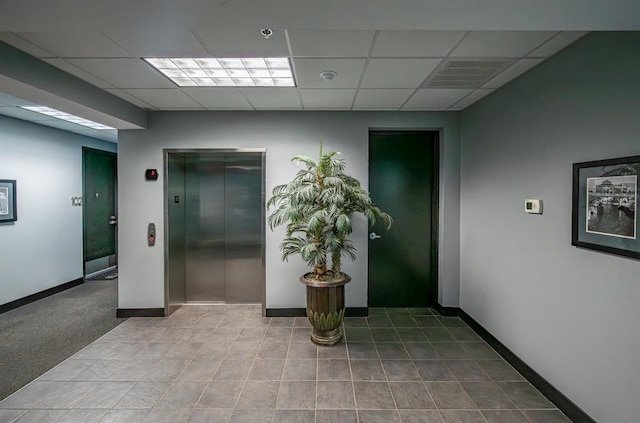 interior space with elevator, a drop ceiling, and baseboards
