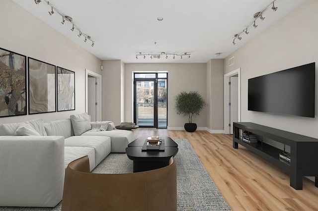 living area featuring track lighting, light wood-style flooring, baseboards, and visible vents