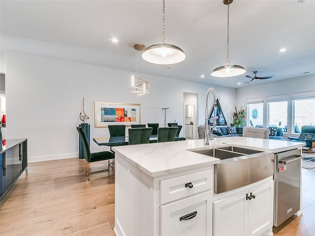 kitchen featuring a center island with sink, light wood-type flooring, dishwasher, and open floor plan