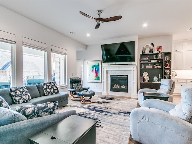 living area featuring ceiling fan, visible vents, a glass covered fireplace, and recessed lighting