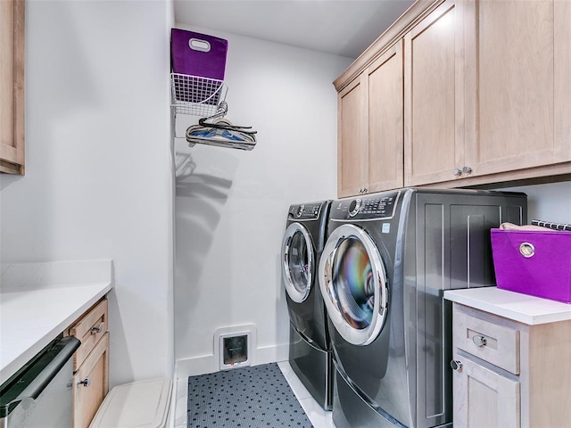 laundry area featuring light tile patterned floors, baseboards, cabinet space, and washer and clothes dryer