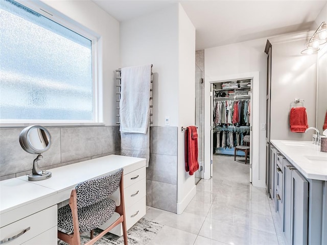 bathroom featuring vanity, tile walls, a spacious closet, and a healthy amount of sunlight