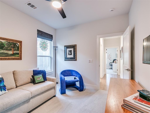 living room with visible vents, light carpet, baseboards, and ceiling fan