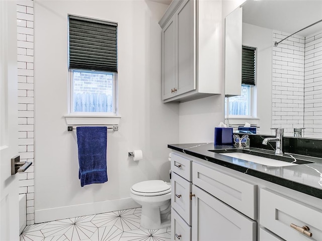 full bathroom with baseboards, toilet, walk in shower, and vanity