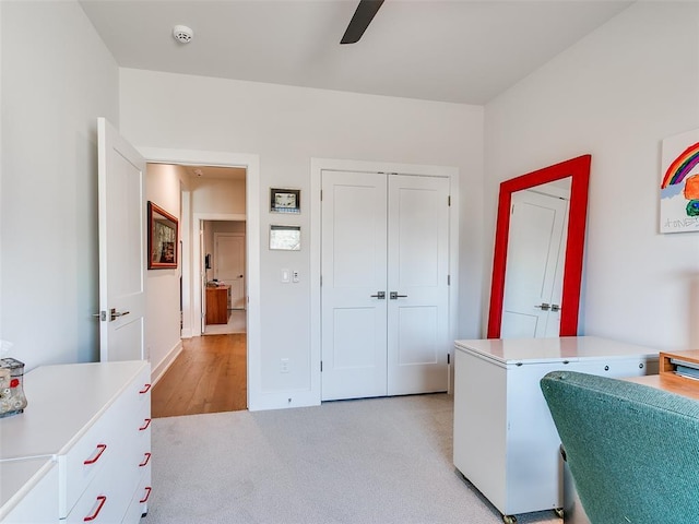 home office featuring a ceiling fan, baseboards, and light carpet