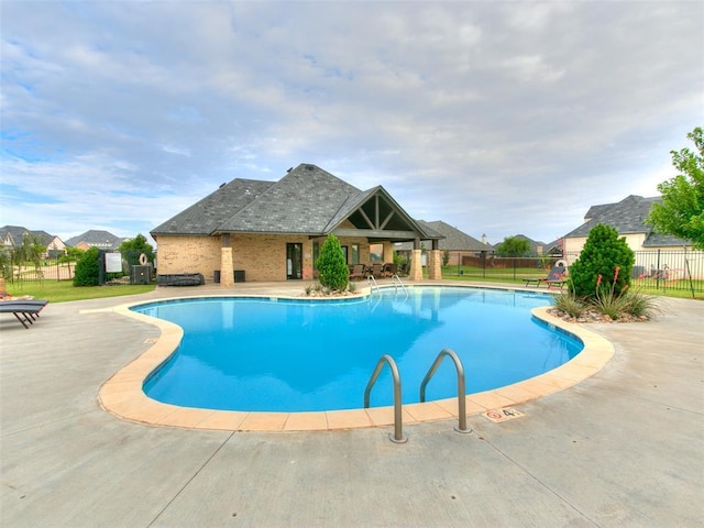 community pool with a patio and fence