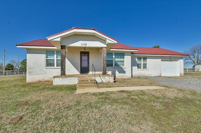 view of front facade featuring fence, an attached garage, a front lawn, brick siding, and metal roof