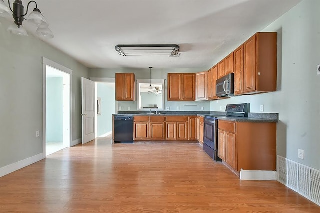 kitchen with dark countertops, visible vents, light wood finished floors, brown cabinetry, and stainless steel appliances