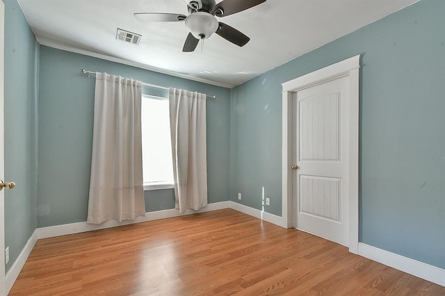 empty room featuring visible vents, a ceiling fan, baseboards, and wood finished floors