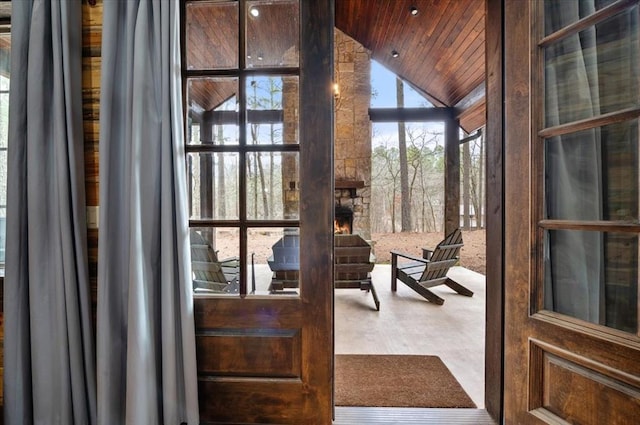 interior space with wood ceiling, an outdoor stone fireplace, and lofted ceiling