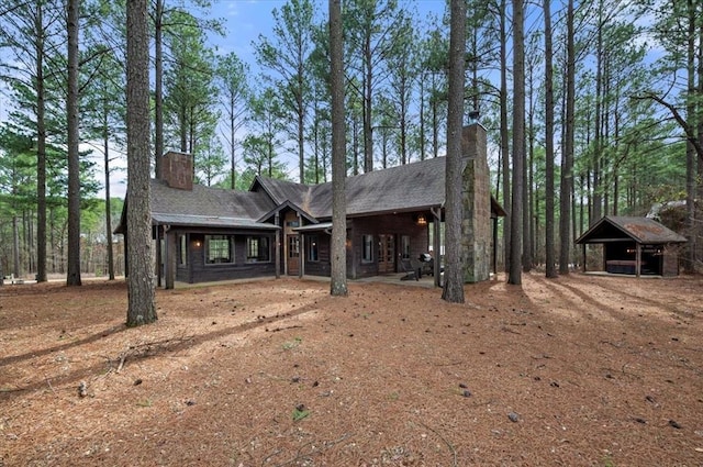 view of front of home featuring a detached carport, roof with shingles, and a chimney