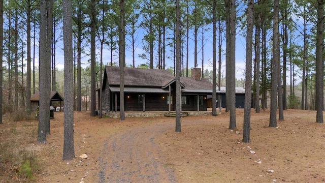 view of front of house with a shingled roof, driveway, and a chimney