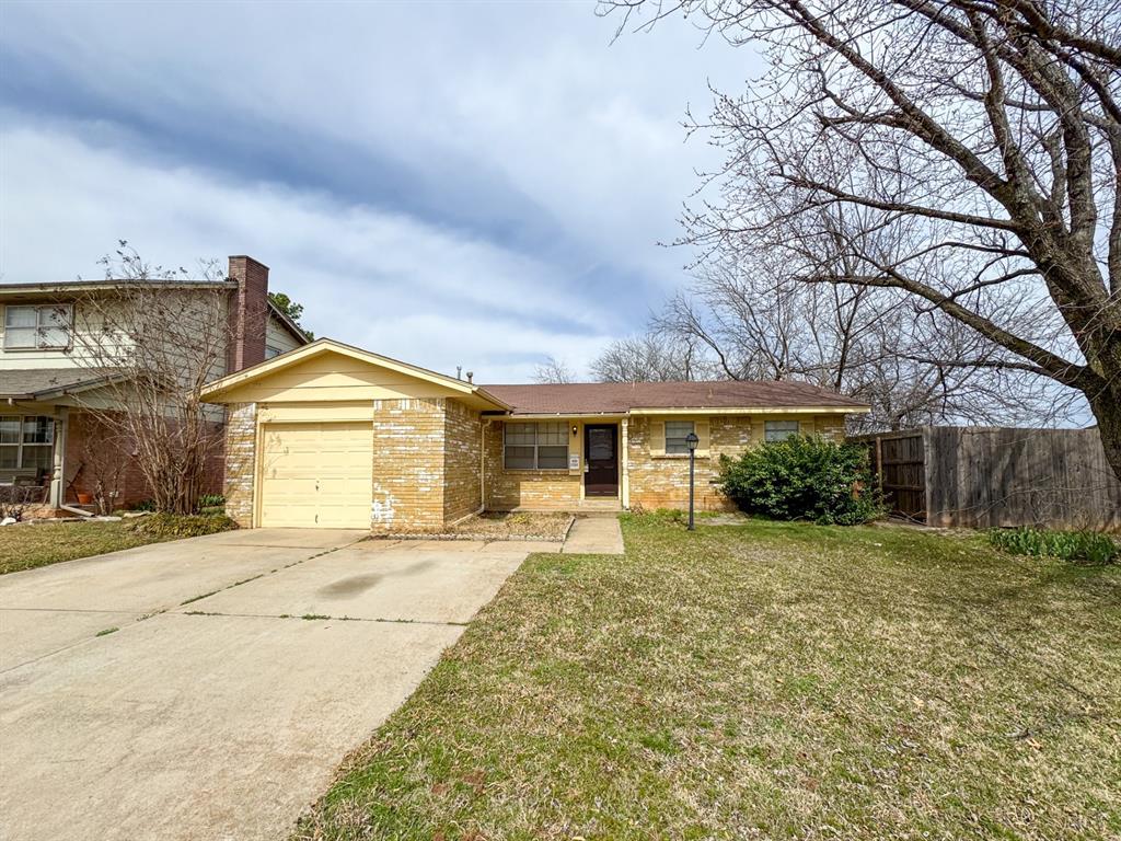 ranch-style house with a front yard, fence, a chimney, concrete driveway, and a garage