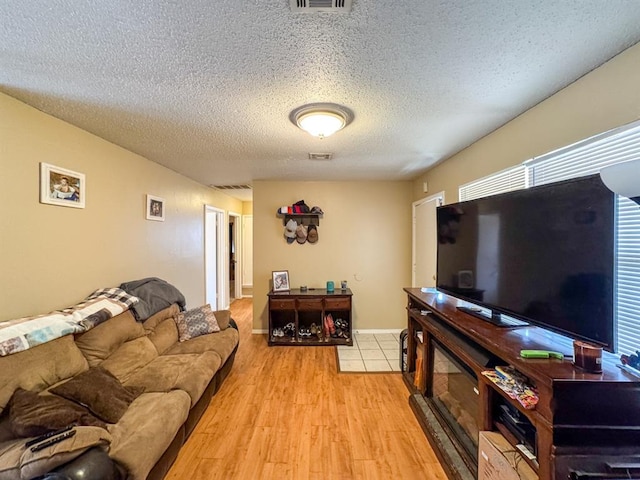 living room featuring light wood-style flooring, visible vents, and a textured ceiling