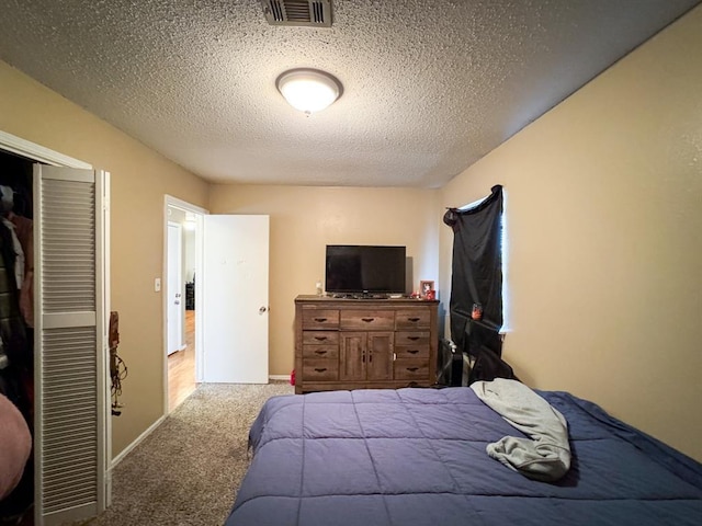 carpeted bedroom featuring a closet, visible vents, a textured ceiling, and baseboards