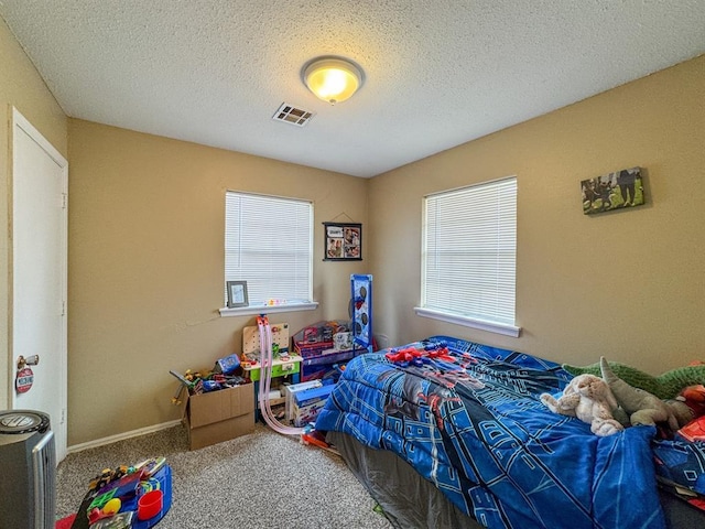 carpeted bedroom featuring visible vents, a textured ceiling, and baseboards