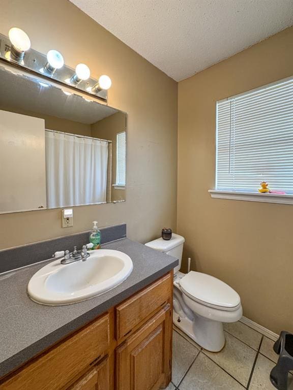 full bathroom with toilet, a textured ceiling, tile patterned flooring, baseboards, and vanity