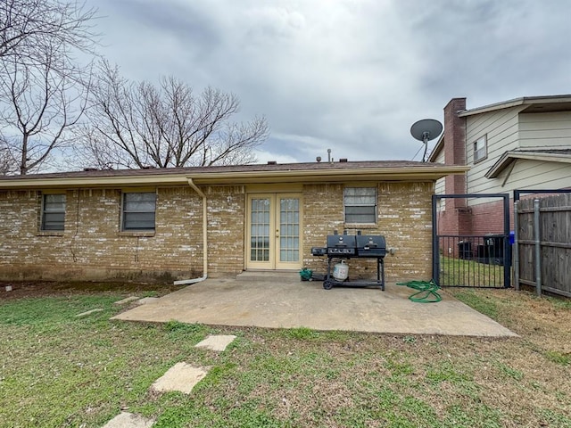 back of property with fence, a yard, french doors, a patio area, and brick siding