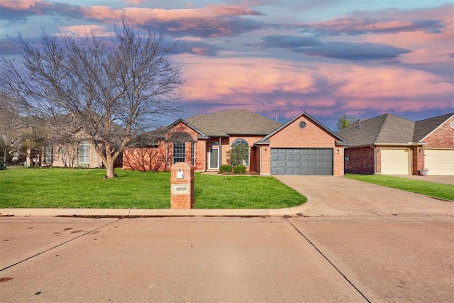 french country inspired facade featuring a yard, driveway, brick siding, and an attached garage