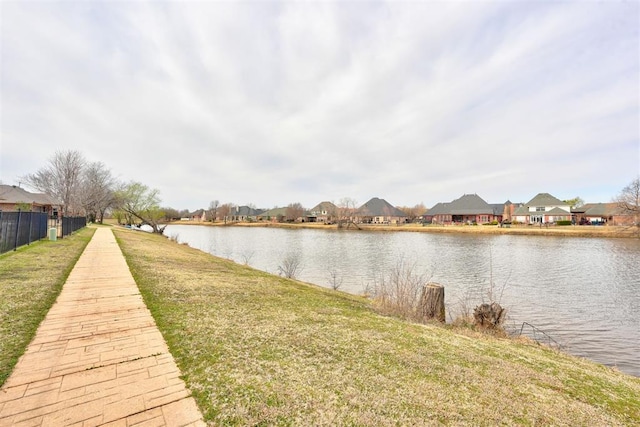 exterior space with a yard, fence, a water view, and a residential view