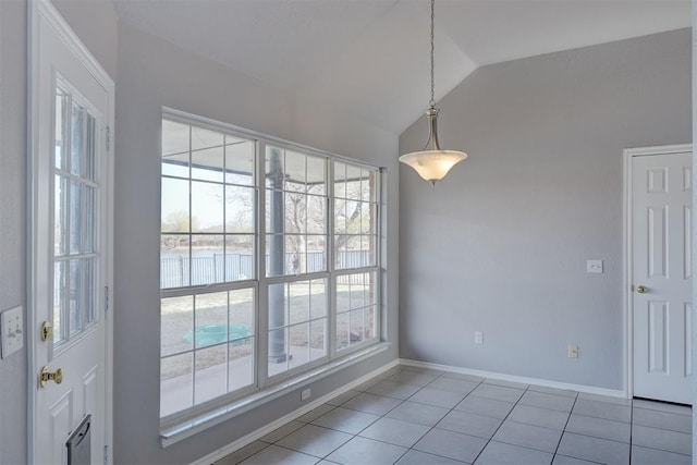 spare room with baseboards, light tile patterned flooring, and vaulted ceiling