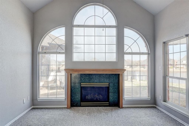 unfurnished living room featuring baseboards, lofted ceiling, carpet, and a fireplace