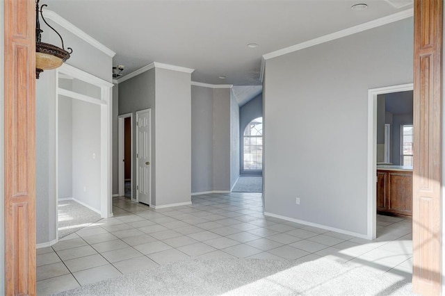 empty room with light tile patterned floors, baseboards, and crown molding