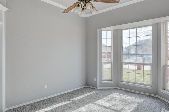 empty room featuring crown molding, carpet flooring, baseboards, and ceiling fan