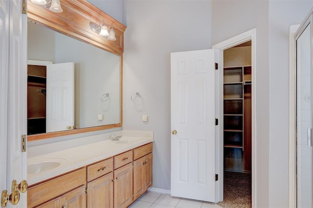 full bathroom with a walk in closet, double vanity, tile patterned flooring, and a sink