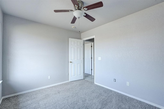 empty room featuring carpet flooring, a ceiling fan, and baseboards