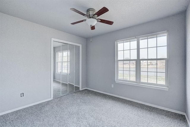 unfurnished bedroom with a closet, baseboards, carpet, and a ceiling fan