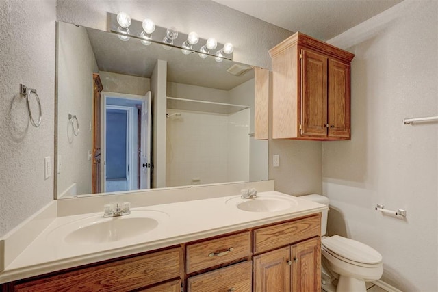 full bathroom with a sink, a shower, toilet, and double vanity