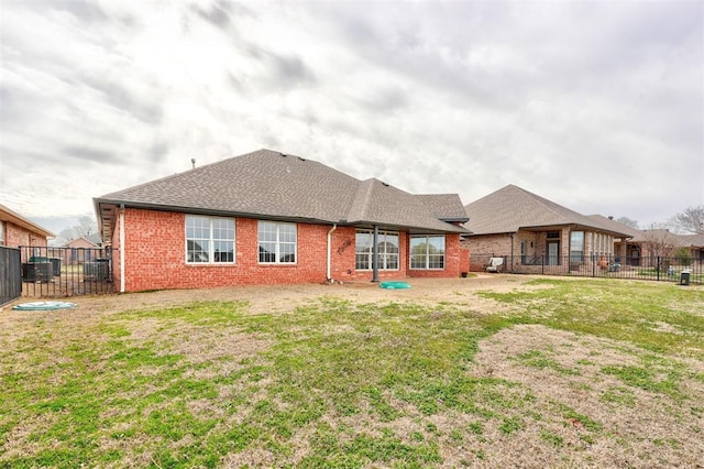 rear view of property featuring brick siding, a shingled roof, a lawn, and fence