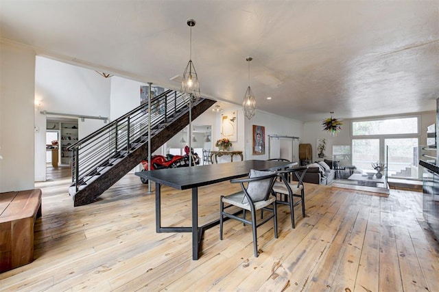 dining room with crown molding, stairway, and light wood finished floors