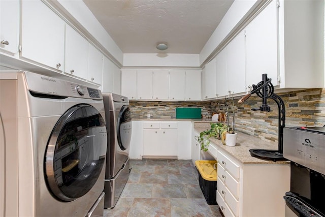 laundry room featuring cabinet space, washer and dryer, and stone finish flooring