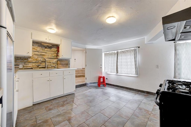 kitchen featuring a sink, tasteful backsplash, white cabinetry, gas stove, and light countertops