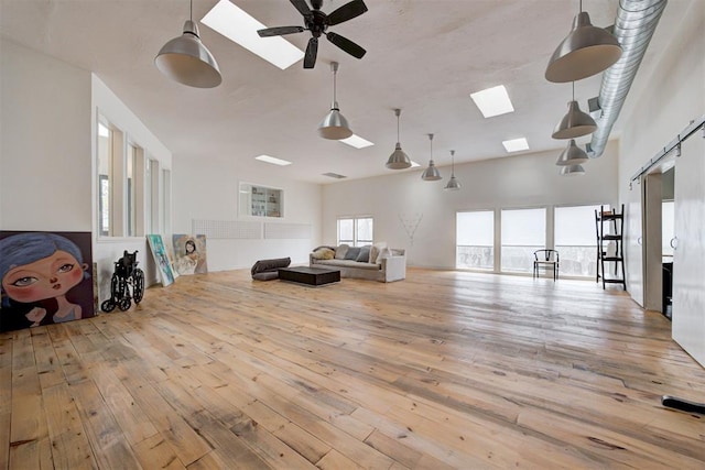 interior space featuring hardwood / wood-style flooring, a skylight, a ceiling fan, and a towering ceiling