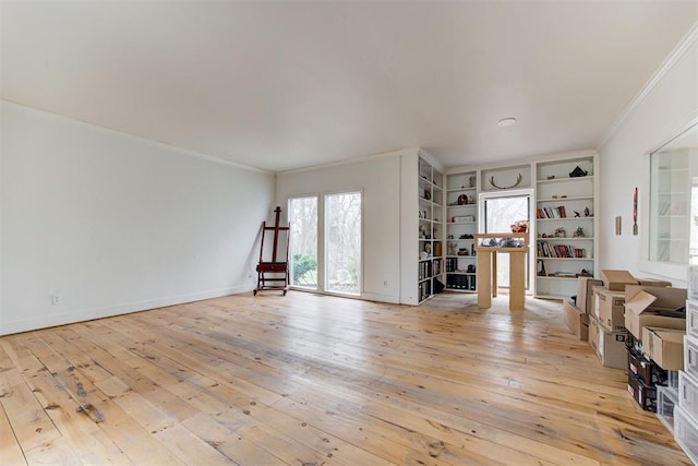 unfurnished living room featuring baseboards, light wood-style floors, and ornamental molding