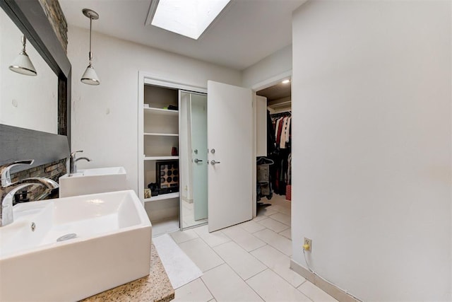 full bathroom featuring tile patterned floors, a skylight, a walk in closet, and a sink