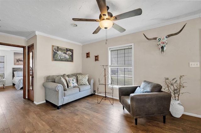 living area with crown molding, baseboards, wood-type flooring, and ceiling fan