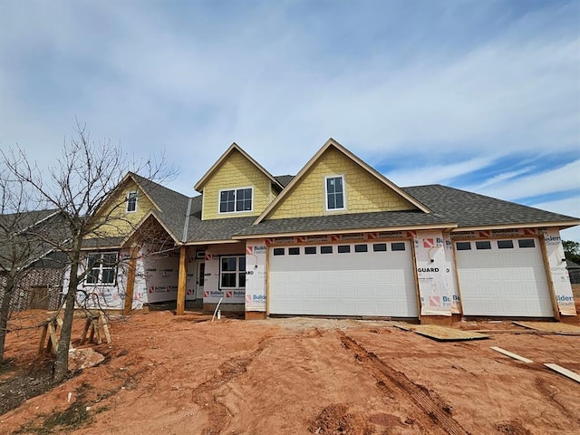 property in mid-construction featuring an attached garage, roof with shingles, and driveway