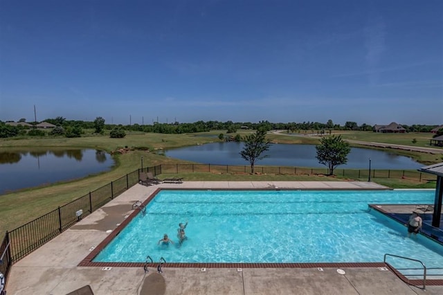 community pool featuring a yard, fence, and a water view