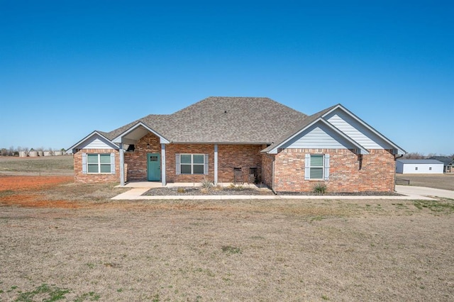 view of front of home with brick siding, a front lawn, and a shingled roof