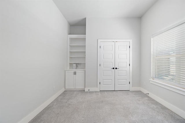 unfurnished bedroom with light colored carpet, baseboards, and a closet